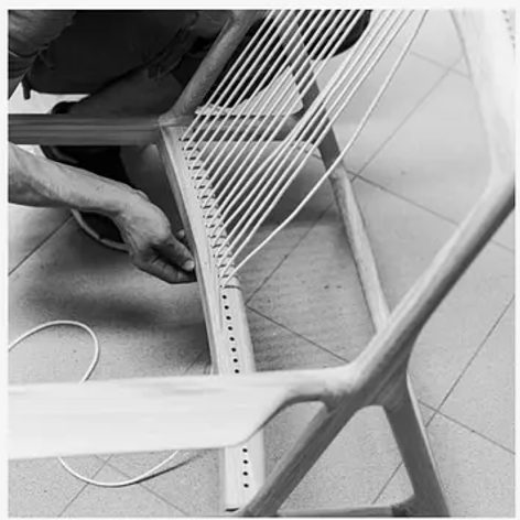 A maker hand-stringing a chair frame during assembly