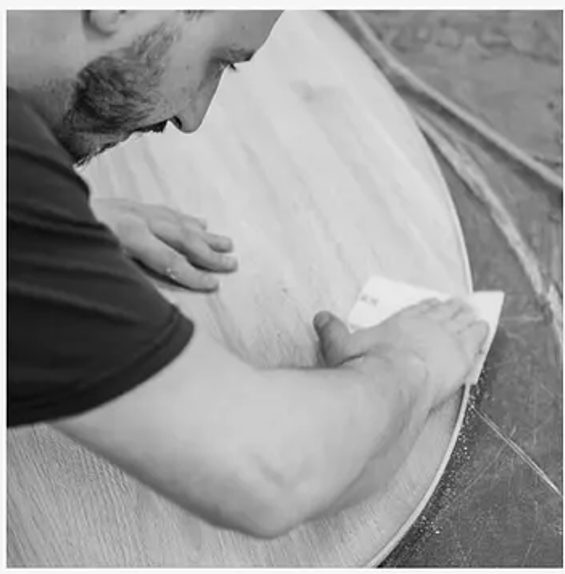 Hand-sanding the edge of a solid wood tabletop
