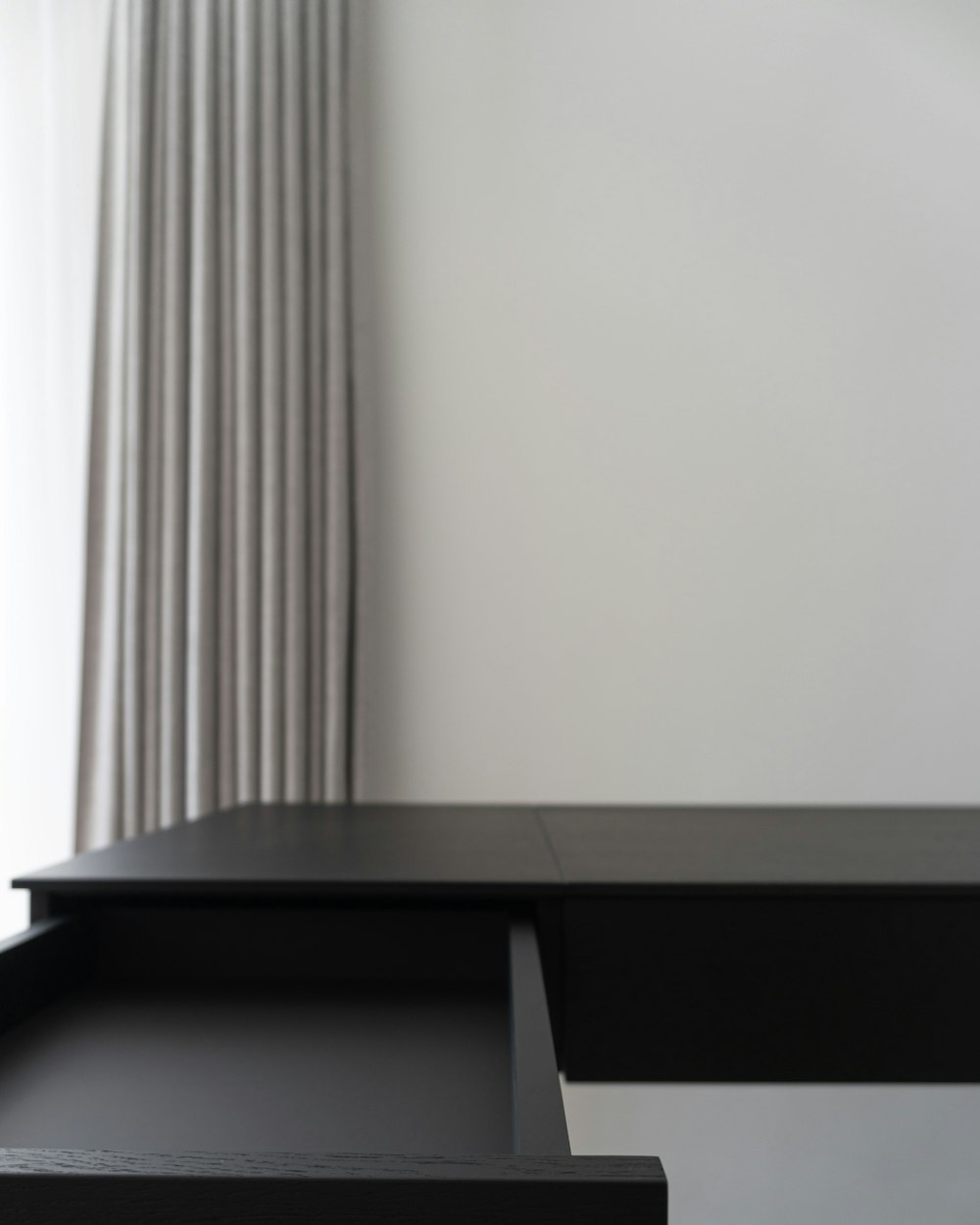 Pivot Work Table — a black desk with two drawers by a window